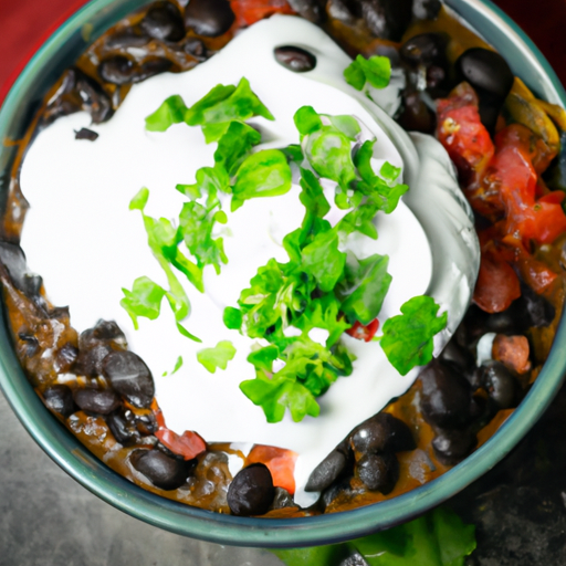 An image showcasing a steaming bowl of hearty black bean chili, richly flavored with spices, adorned with vibrant chunks of vegetables, and topped with a dollop of tangy sour cream and a sprinkle of fresh cilantro